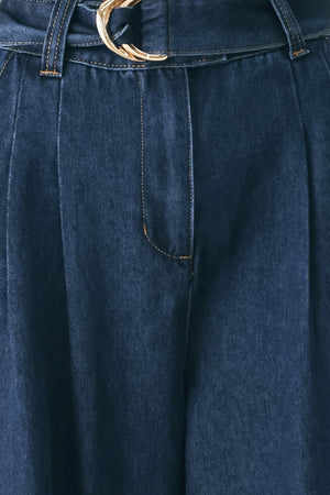 A person wearing dark blue wide-leg denim pants with a rolled cuff and a gold-tone belt buckle | FREEMARKET