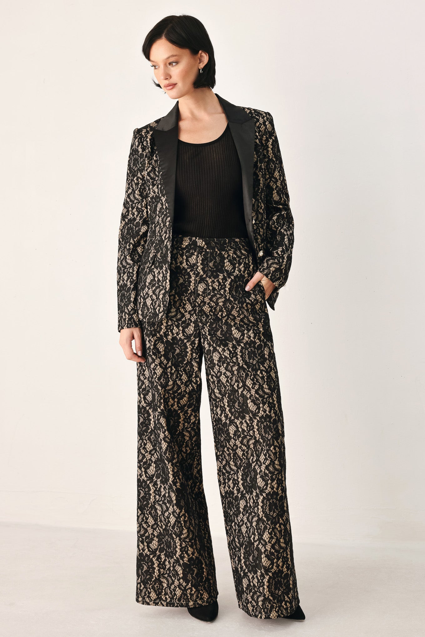 A model wearing high-waisted, wide-leg trousers featuring a black and beige floral lace pattern | FREEMARKET