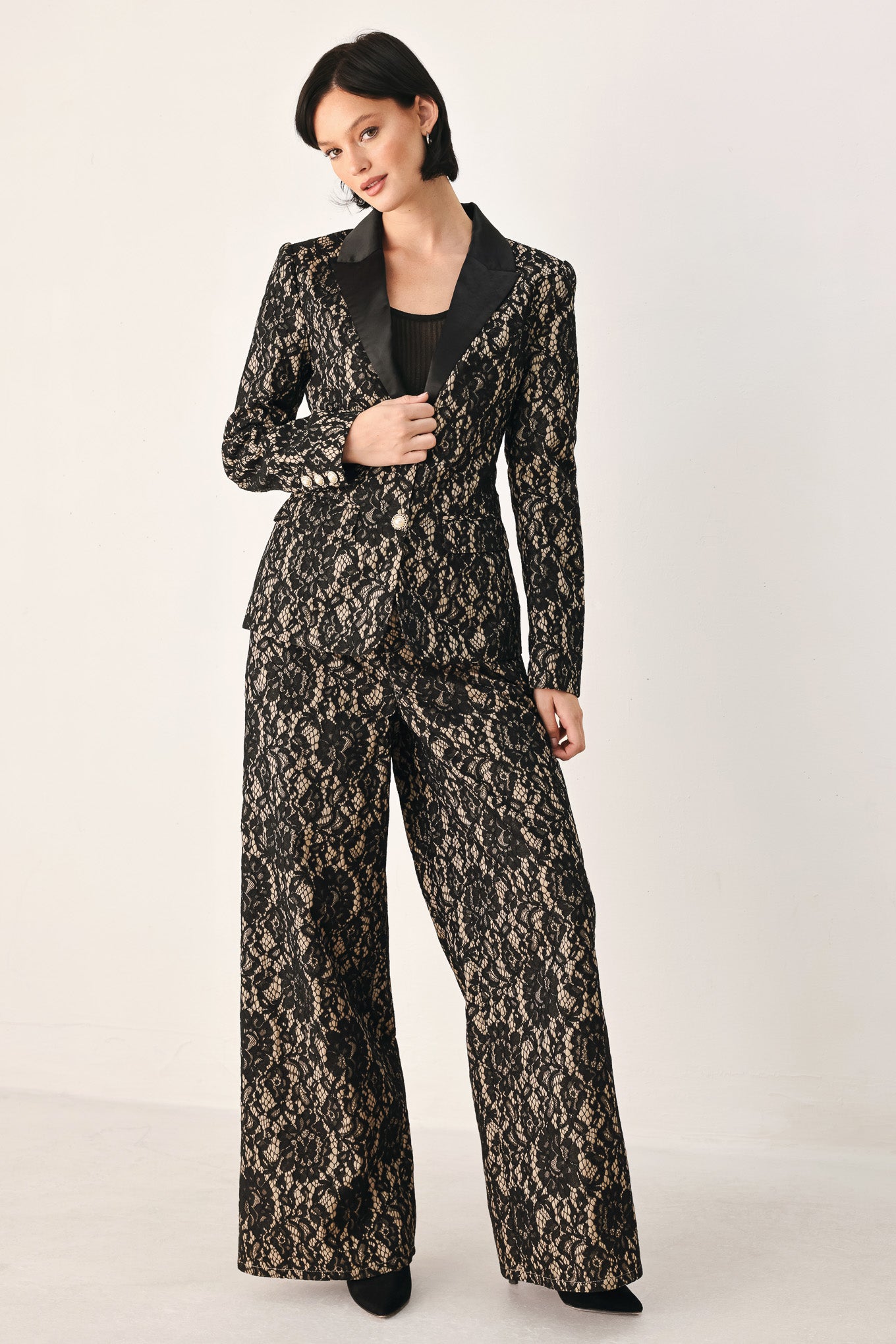 A model wearing high-waisted, wide-leg trousers featuring a black and beige floral lace pattern | FREEMARKET