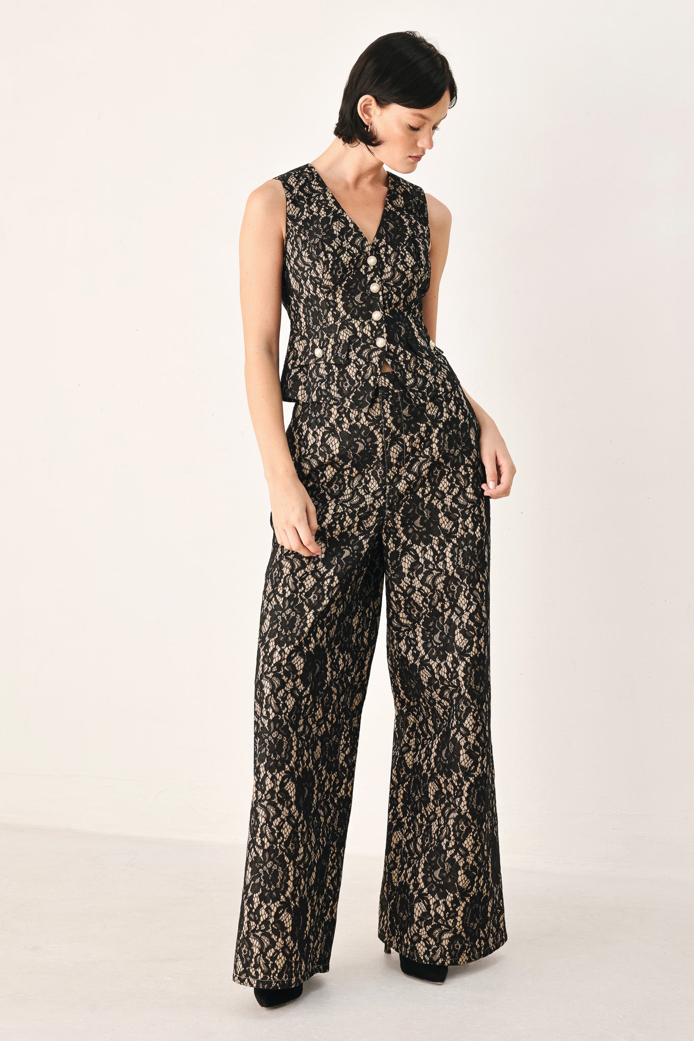 A model wearing high-waisted, wide-leg trousers featuring a black and beige floral lace pattern | FREEMARKET