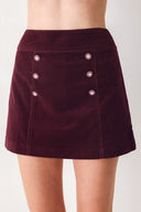 Woman wearing a burgundy velvet skort with buttons | FREEMARKET