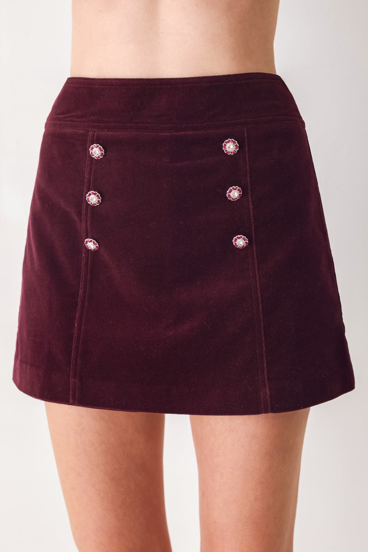 Woman wearing a burgundy velvet skort with buttons | FREEMARKET