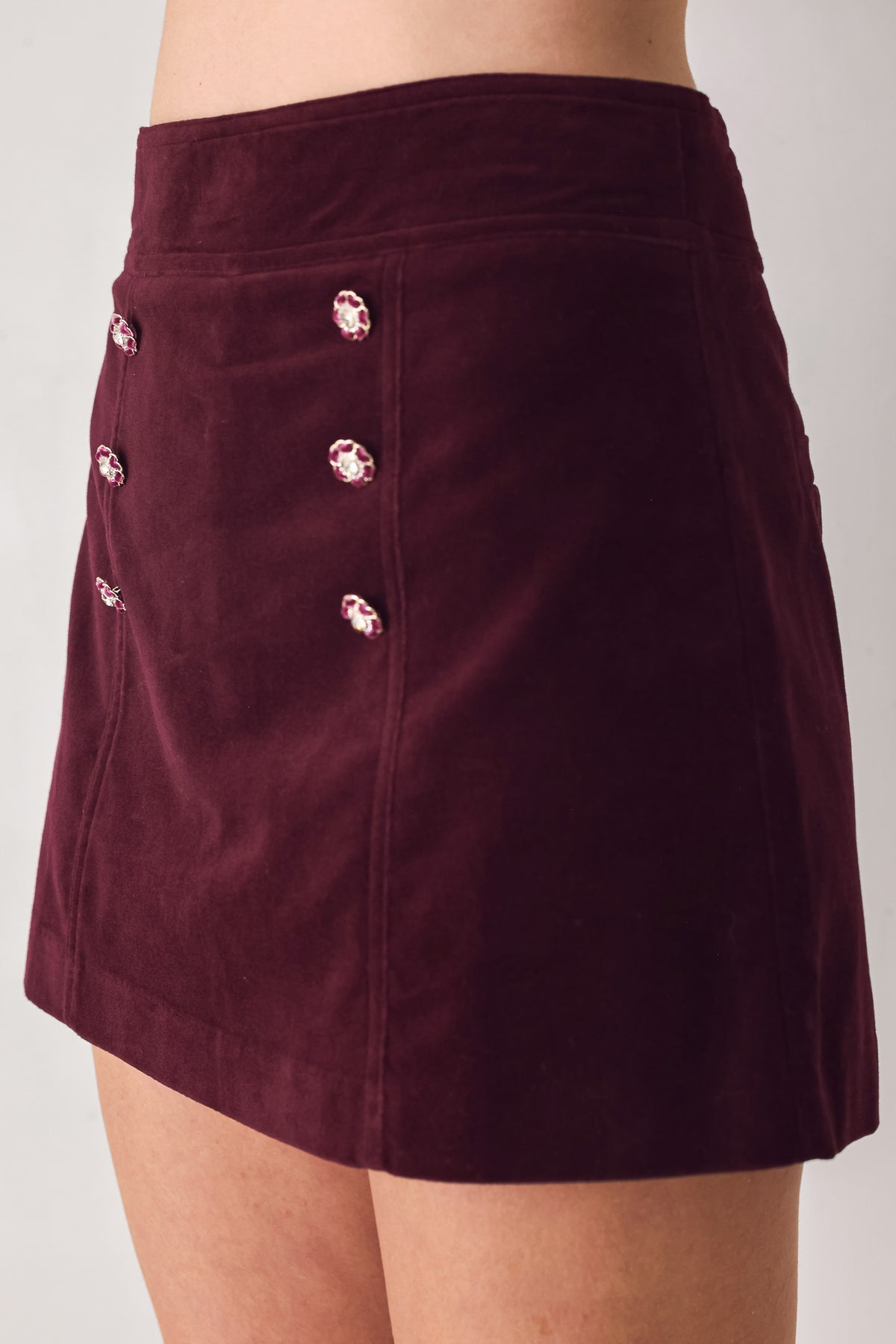 Woman wearing a burgundy velvet skort with buttons | FREEMARKET