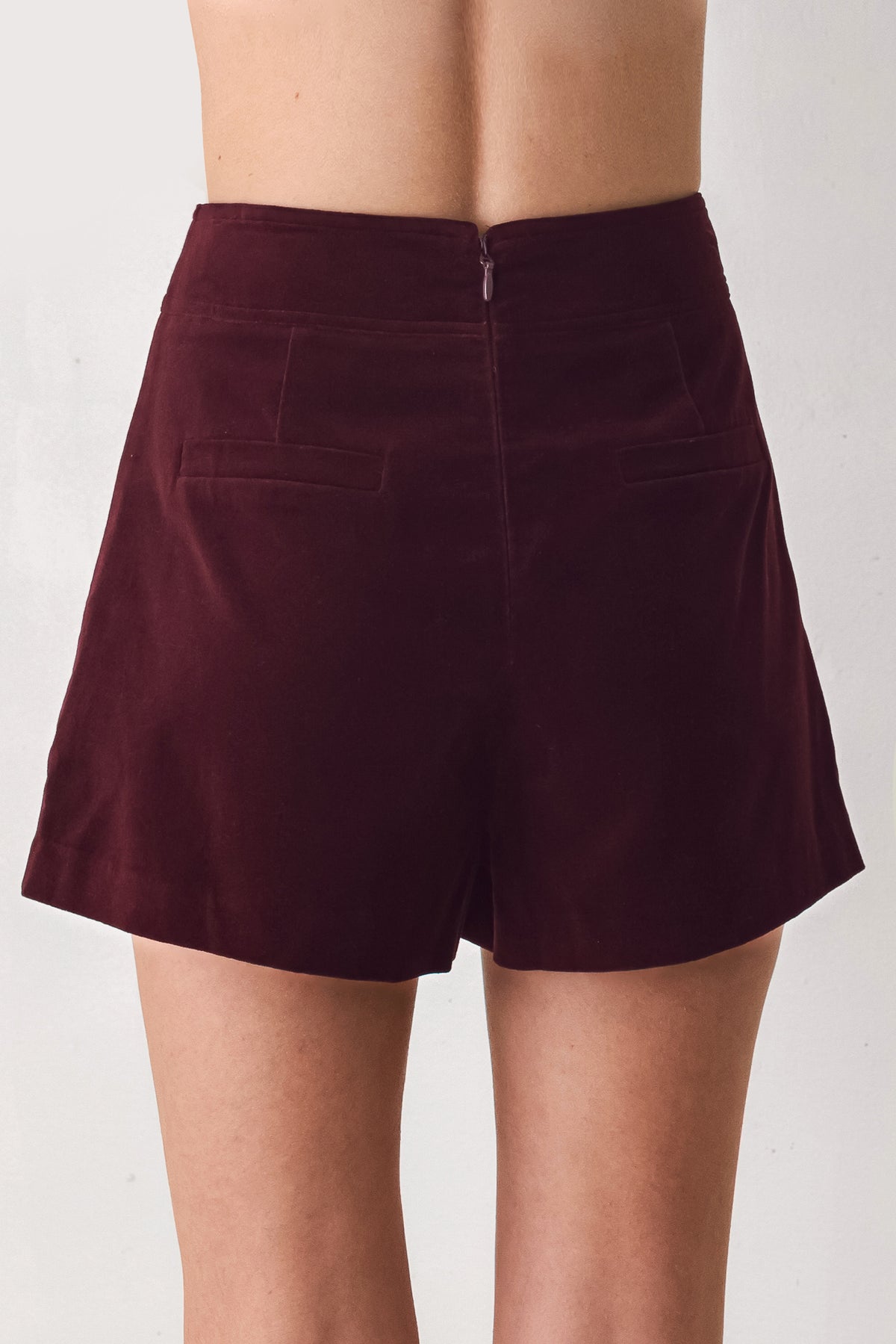 Woman wearing a burgundy velvet skort with buttons | FREEMARKET