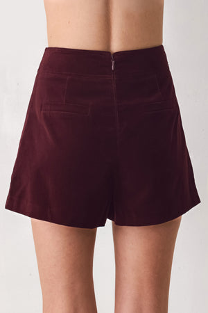Woman wearing a burgundy velvet skort with buttons | FREEMARKET
