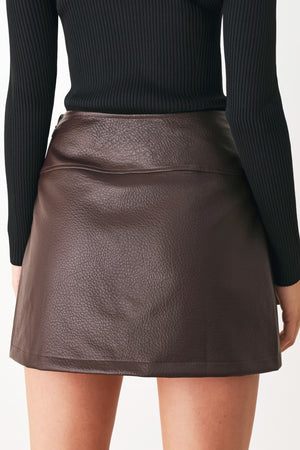 A dark brown faux-leather mini skort with a pebbled texture, worn by a model | FREEMARKET