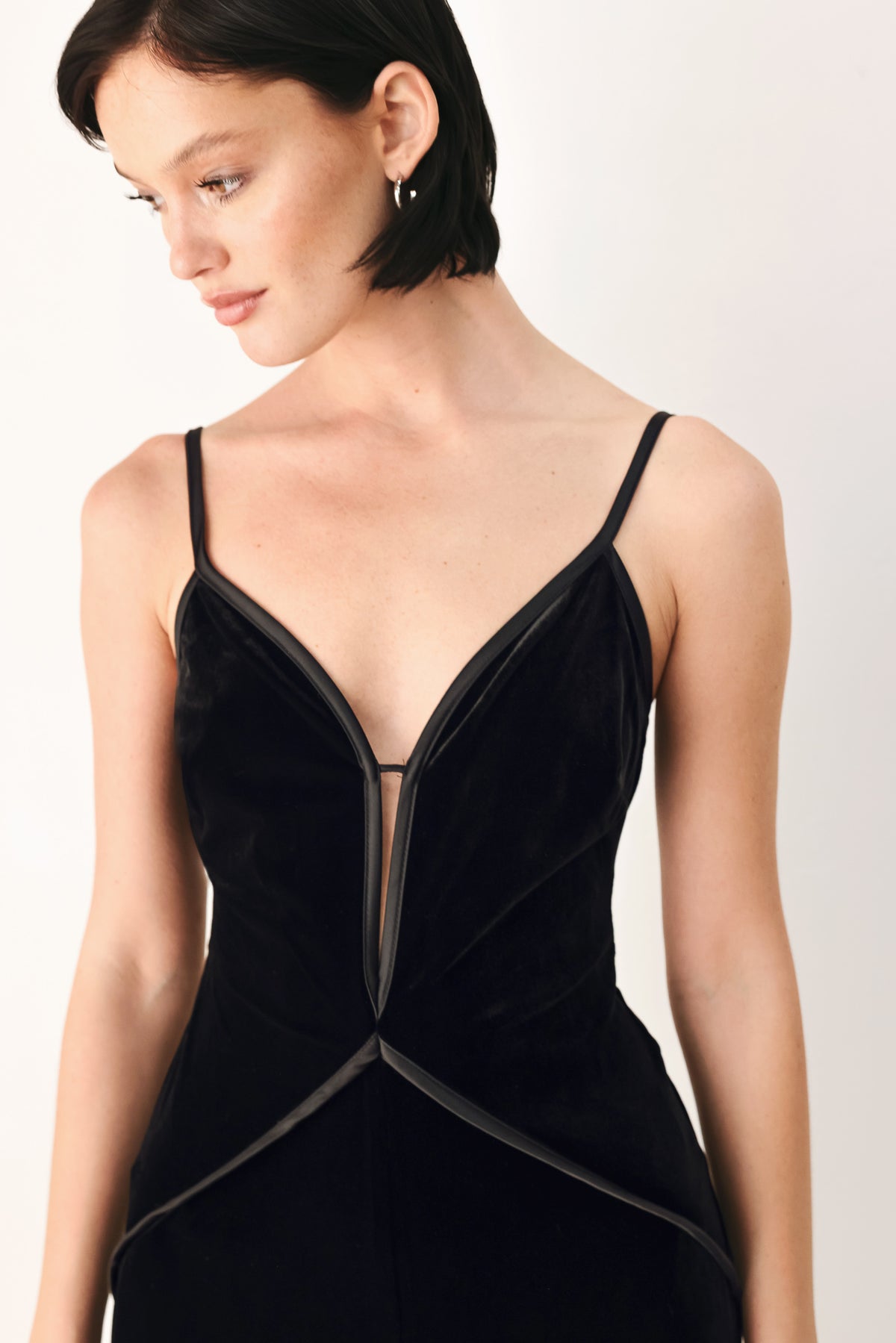 A woman modeling a black velvet wide-leg jumpsuit with thin straps, a plunging neckline | FREEMARKET