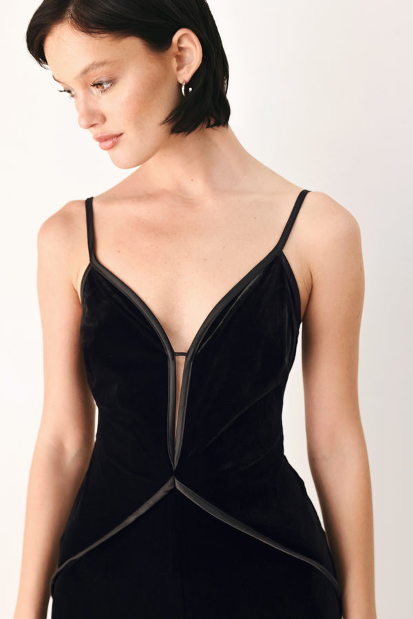 A woman modeling a black velvet wide-leg jumpsuit with thin straps, a plunging neckline | FREEMARKET