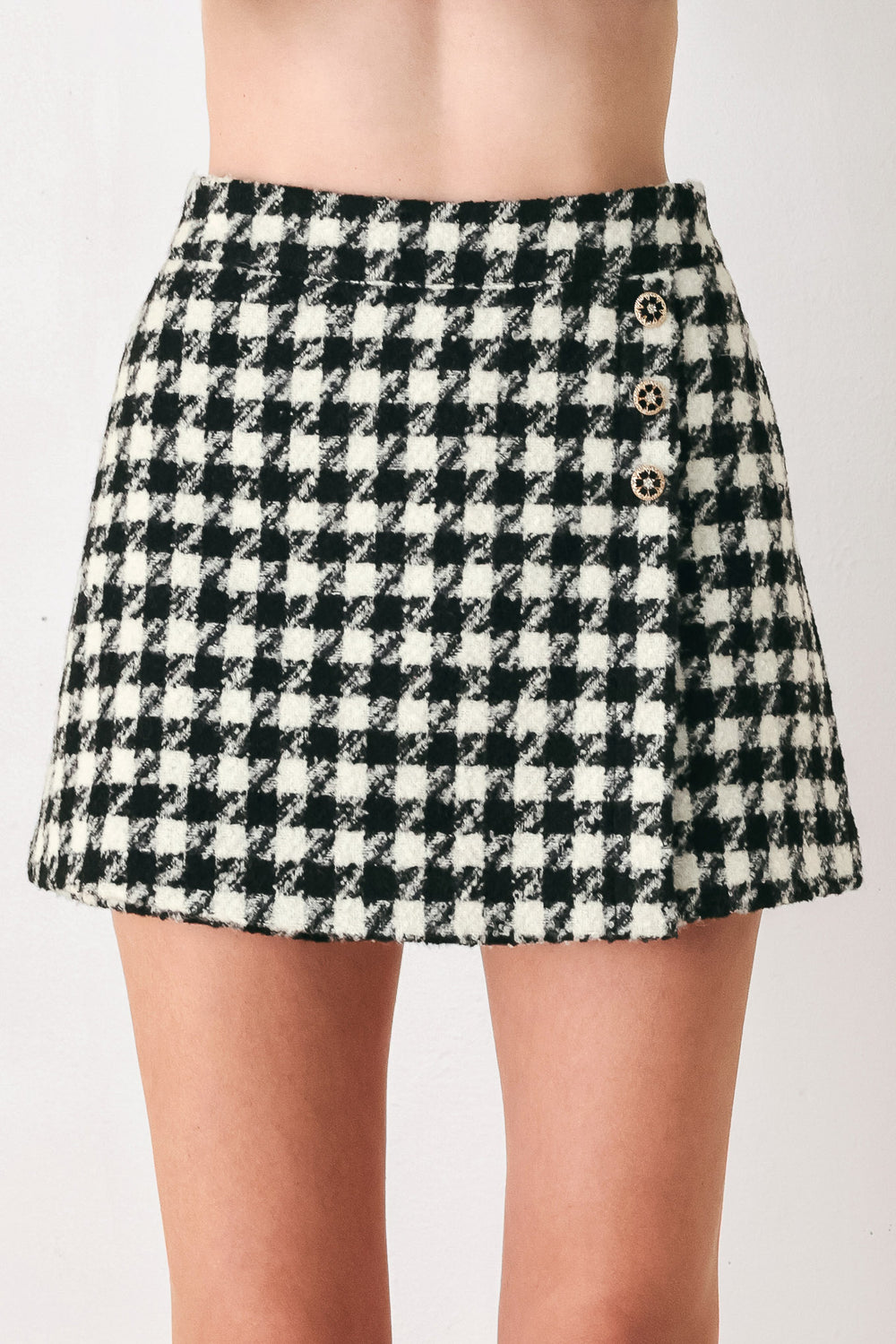 Woman wearing a high waisted black and white houndstooth skort with buttons | FREEMARKET