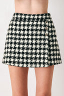Woman wearing a high waisted black and white houndstooth skort with buttons | FREEMARKET