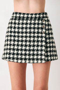 Woman wearing a high waisted black and white houndstooth skort with buttons | FREEMARKET