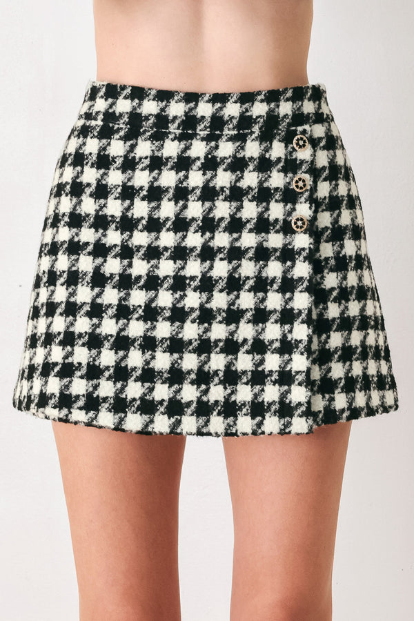 Woman wearing a high waisted black and white houndstooth skort with buttons | FREEMARKET
