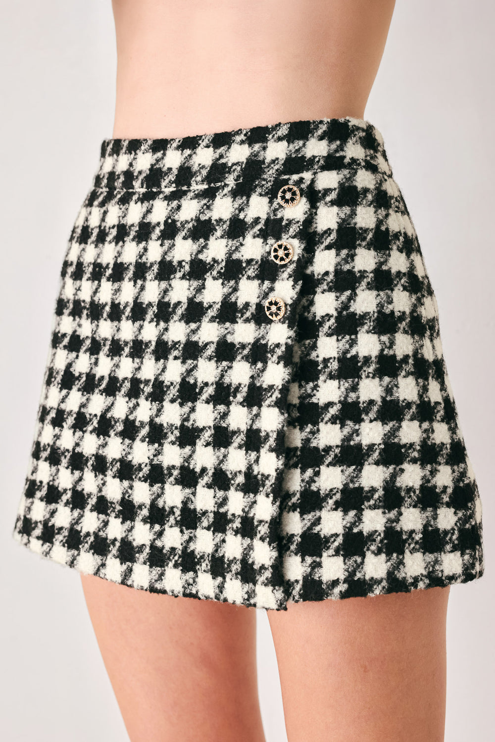 Woman wearing a high waisted black and white houndstooth skort with buttons | FREEMARKET