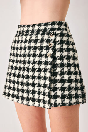 Woman wearing a high waisted black and white houndstooth skort with buttons | FREEMARKET