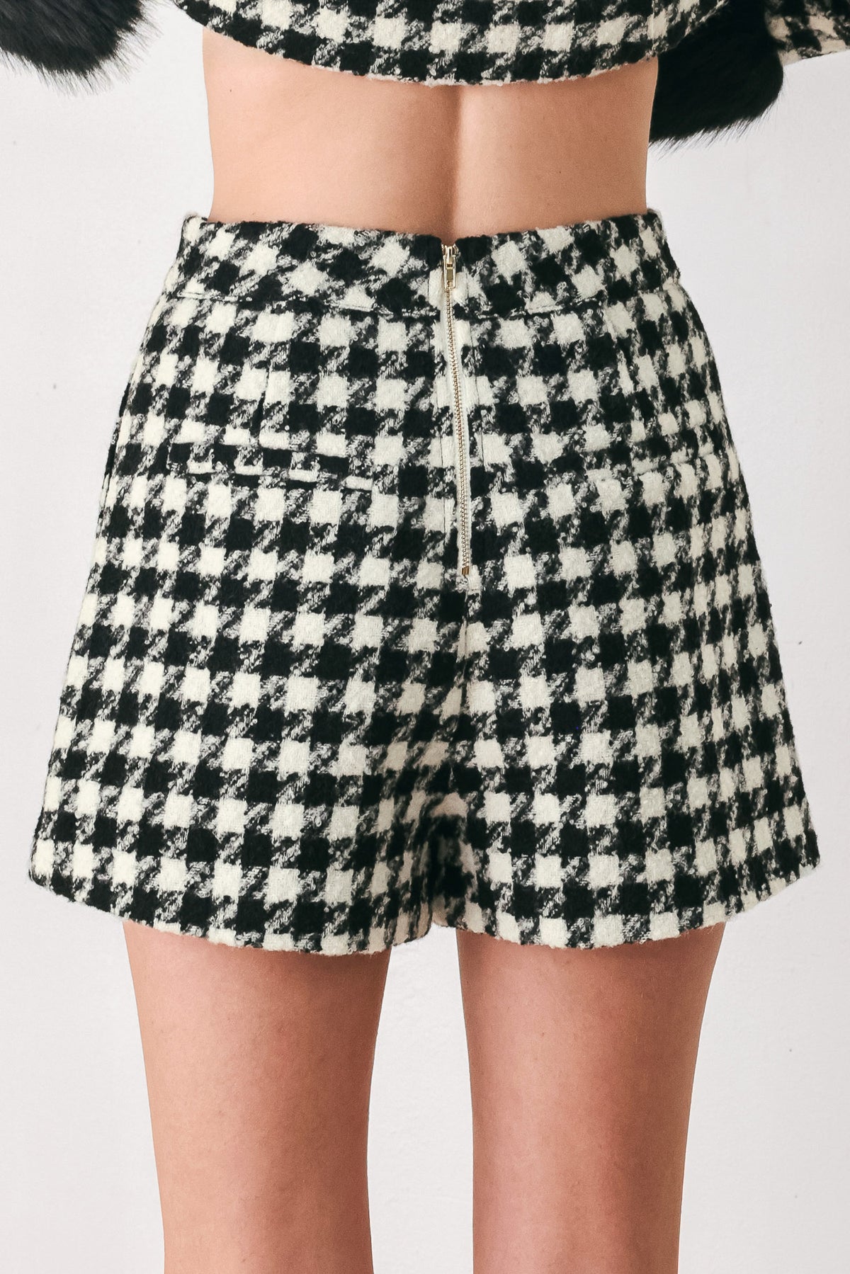 Woman wearing a high waisted black and white houndstooth skort with buttons | FREEMARKET