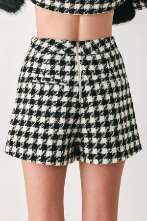 Woman wearing a high waisted black and white houndstooth skort with buttons | FREEMARKET