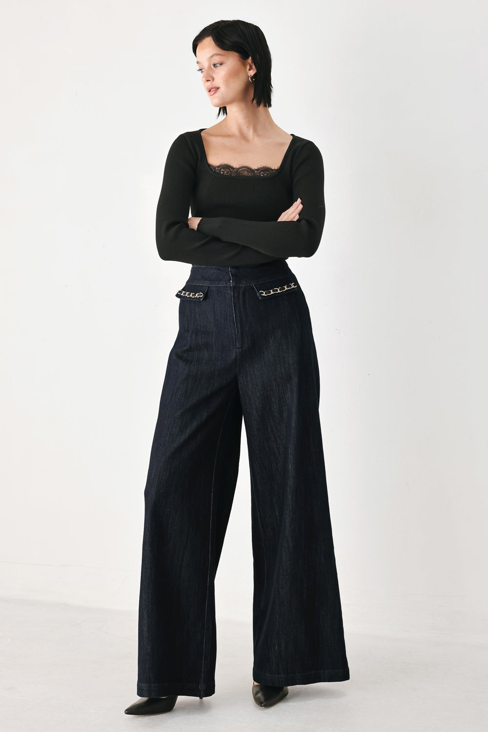 A model wearing dark indigo wide-leg denim jeans with gold chain embellishments on the front pockets | FREEMARKET