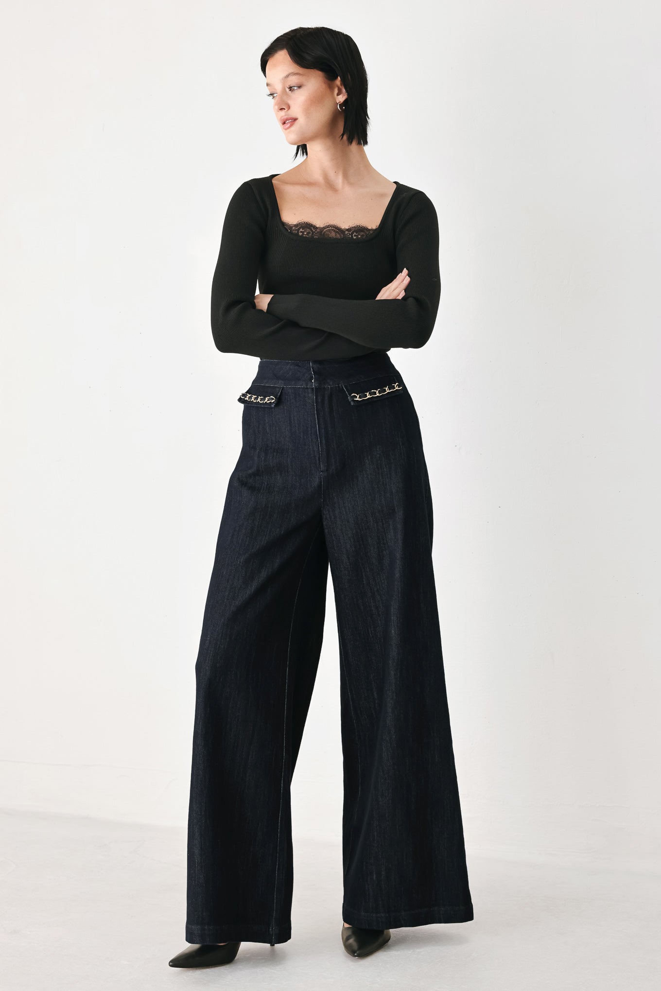 A model wearing dark indigo wide-leg denim jeans with gold chain embellishments on the front pockets | FREEMARKET