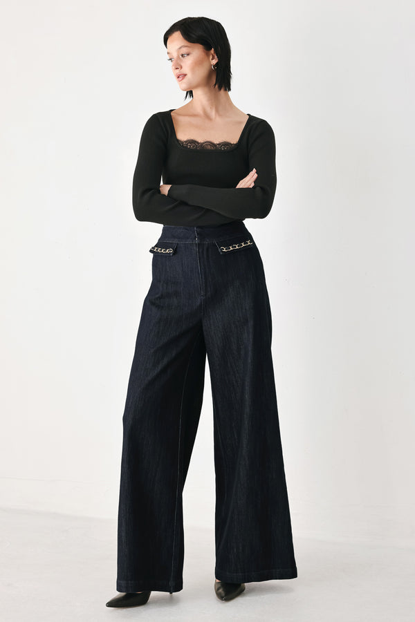 A model wearing dark indigo wide-leg denim jeans with gold chain embellishments on the front pockets | FREEMARKET