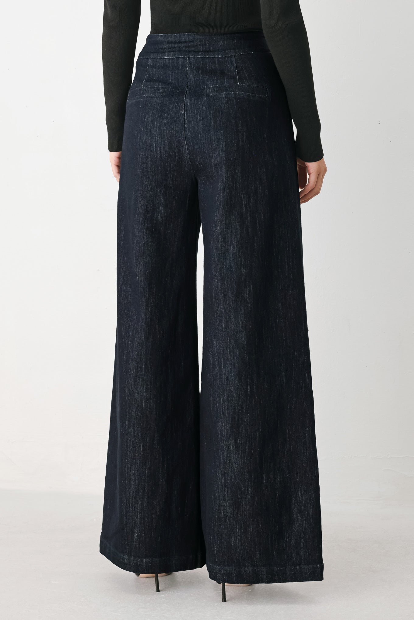 A model wearing dark indigo wide-leg denim jeans with gold chain embellishments on the front pockets | FREEMARKET