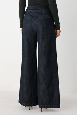 A model wearing dark indigo wide-leg denim jeans with gold chain embellishments on the front pockets | FREEMARKET