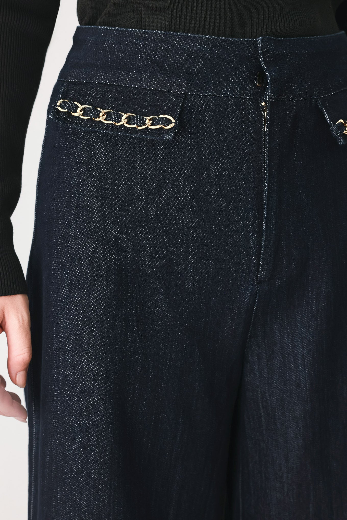 A model wearing dark indigo wide-leg denim jeans with gold chain embellishments on the front pockets | FREEMARKET