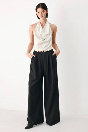 A model wearing a sleeveless jumpsuit with draped white top and black wide-leg trousers, and a thin gold belt with a round buckle | FREEMARKET