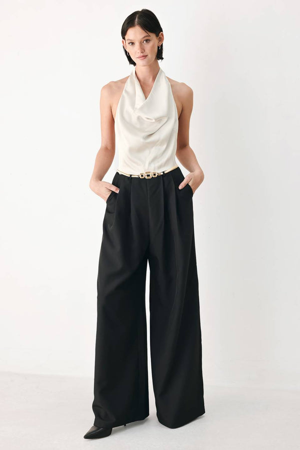 A model wearing a sleeveless jumpsuit with draped white top and black wide-leg trousers, and a thin gold belt with a round buckle | FREEMARKET