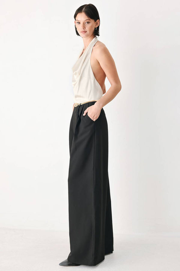 A model wearing a sleeveless jumpsuit with draped white top and black wide-leg trousers, and a thin gold belt with a round buckle | FREEMARKET