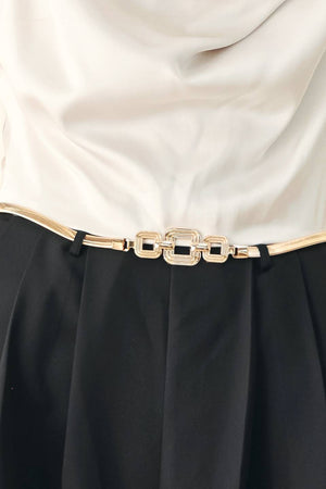 A model wearing a sleeveless jumpsuit with draped white top and black wide-leg trousers, and a thin gold belt with a round buckle | FREEMARKET