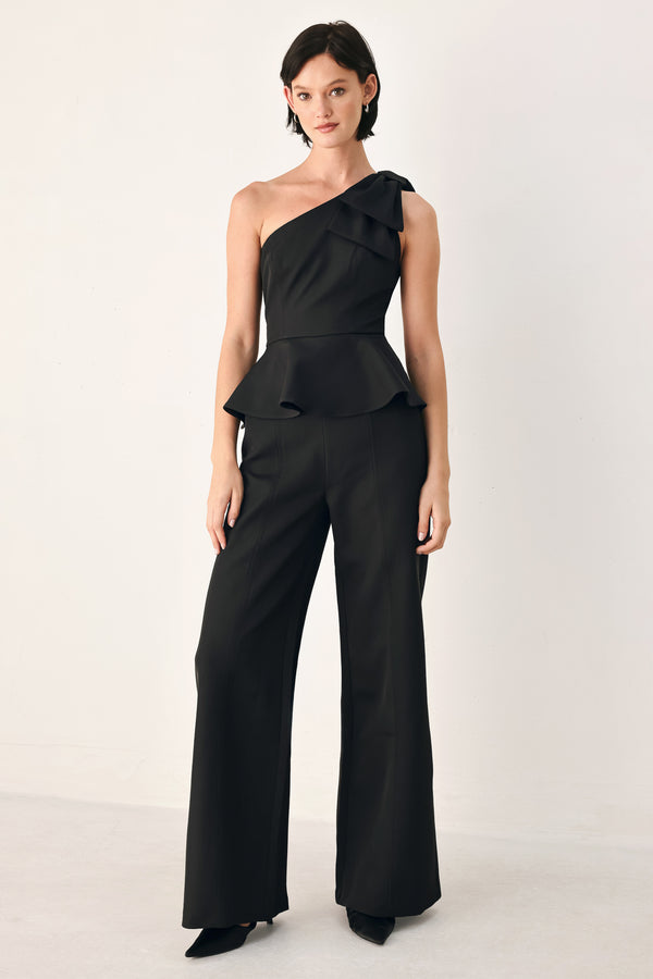A model wearing a black one-shoulder jumpsuit with a ruffled bodice and wide-leg trousers | FREEMARKET