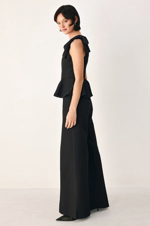 A model wearing a black one-shoulder jumpsuit with a ruffled bodice and wide-leg trousers | FREEMARKET
