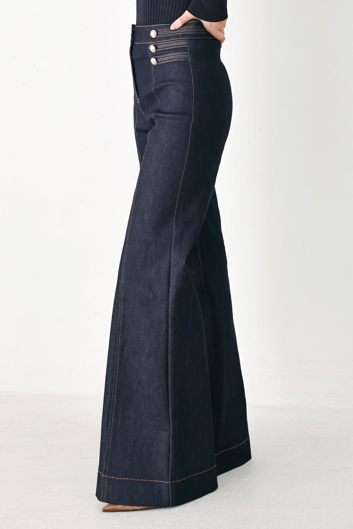 A model wearing dark blue wide-leg denim jeans with decorative silver buttons on the front | FREEMARKET