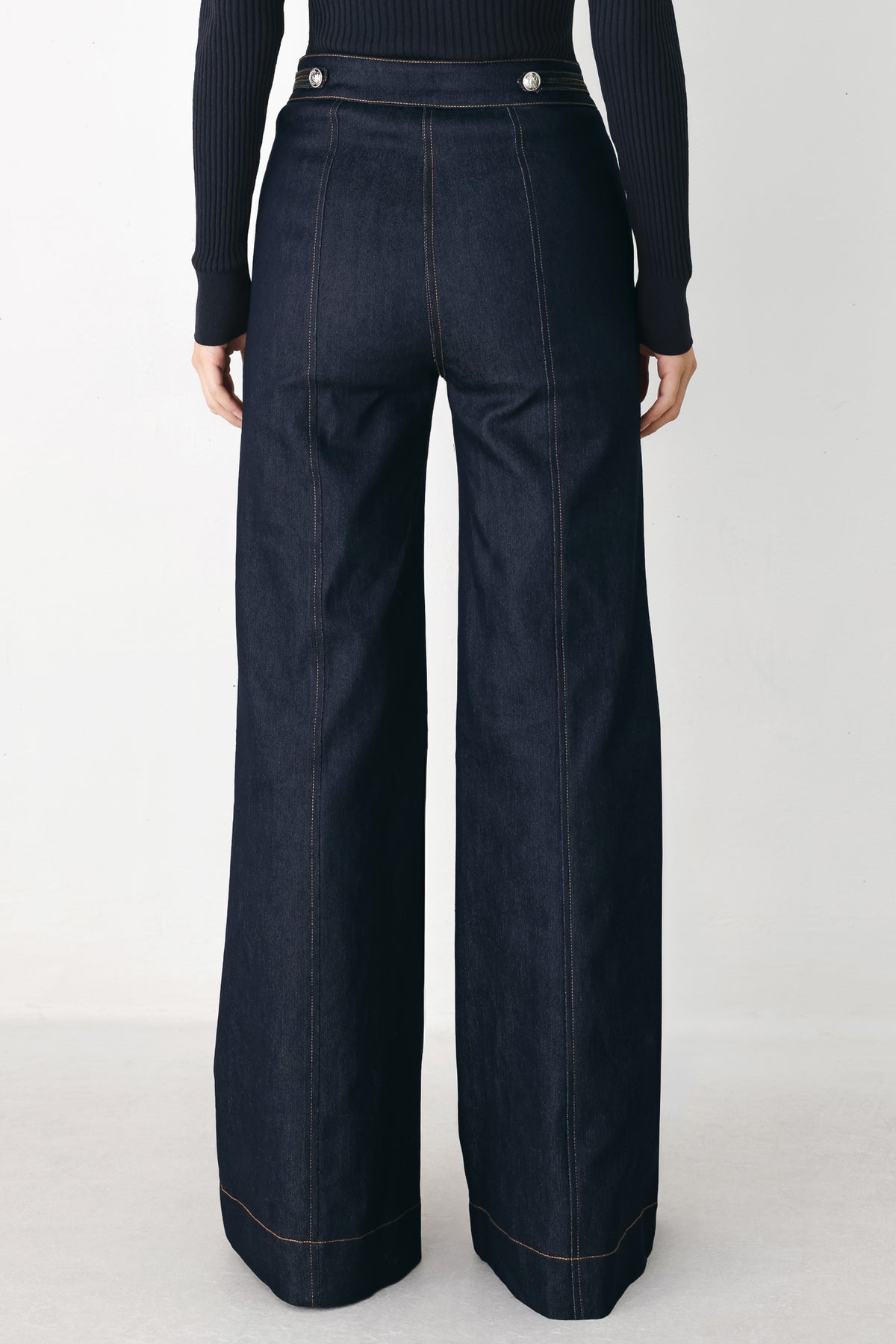A model wearing dark blue wide-leg denim jeans with decorative silver buttons on the front | FREEMARKET