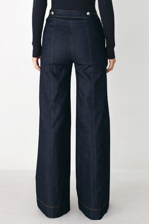 A model wearing dark blue wide-leg denim jeans with decorative silver buttons on the front | FREEMARKET