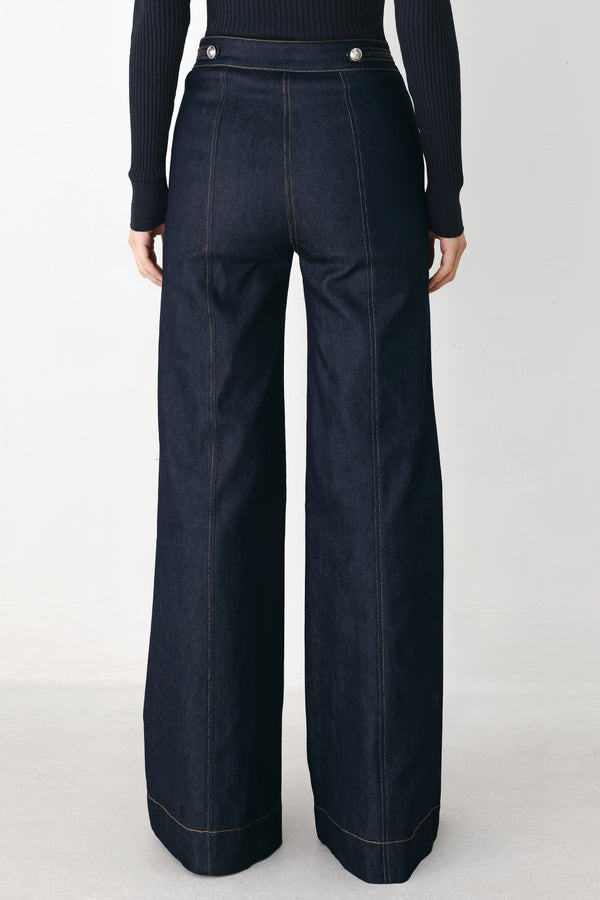 A model wearing dark blue wide-leg denim jeans with decorative silver buttons on the front | FREEMARKET