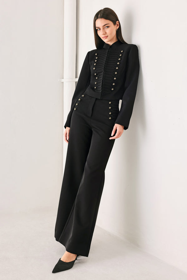 Woman wearing a pair of black high waisted pants with buttons going from the waist to the hips and braiding | FREEMARKET