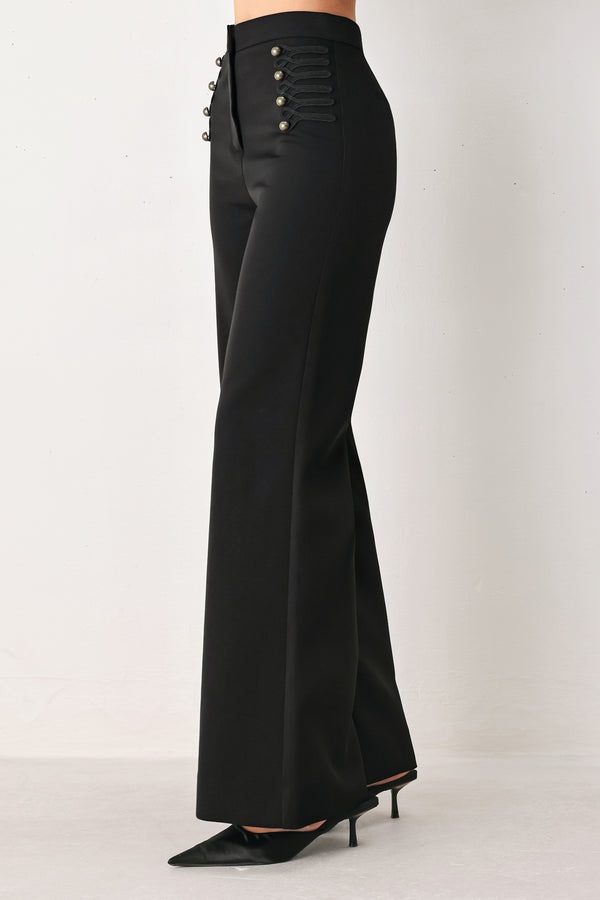 Woman wearing a pair of black high waisted pants with buttons going from the waist to the hips and braiding | FREEMARKET
