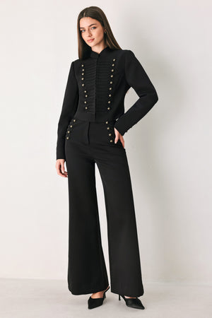 Woman wearing a pair of black high waisted pants with buttons going from the waist to the hips and braiding | FREEMARKET