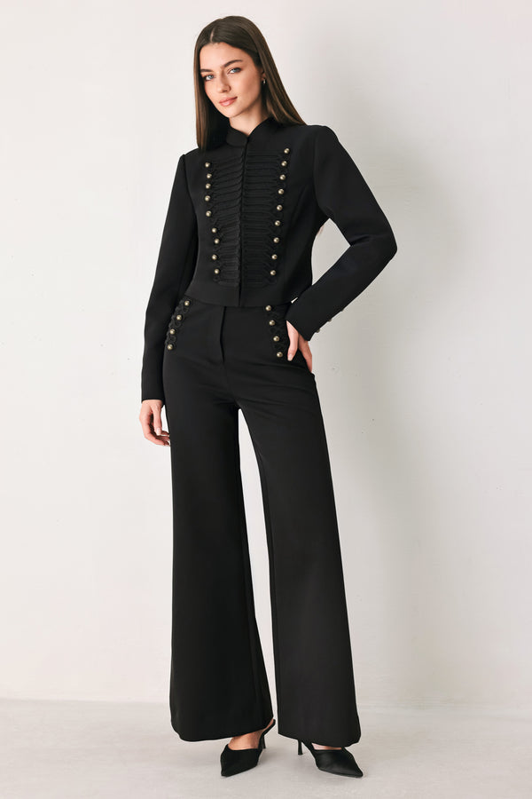 Woman wearing a pair of black high waisted pants with buttons going from the waist to the hips and braiding | FREEMARKET