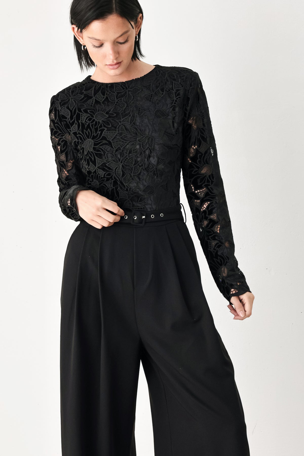 A woman modeling a black long-sleeve jumpsuit with a lace bodice and wide-leg trousers | FREEMARKET