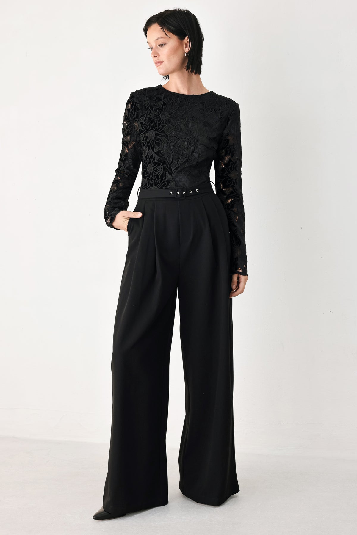 A woman modeling a black long-sleeve jumpsuit with a lace bodice and wide-leg trousers | FREEMARKET