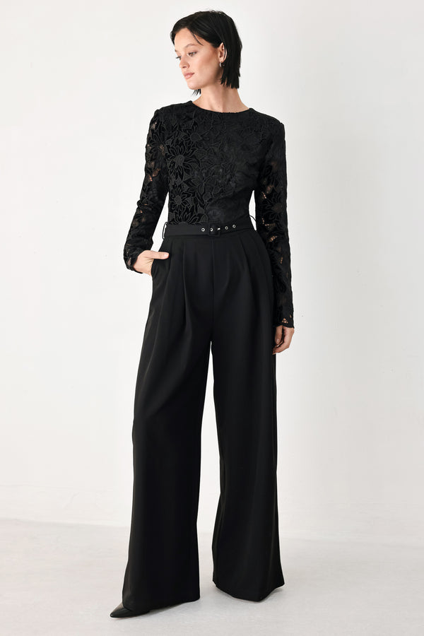 A woman modeling a black long-sleeve jumpsuit with a lace bodice and wide-leg trousers | FREEMARKET