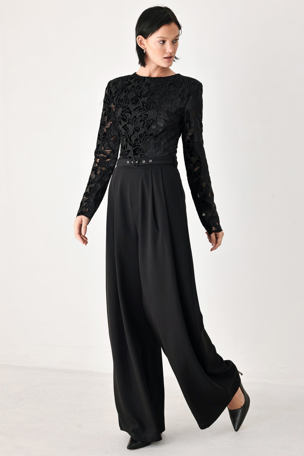 A woman modeling a black long-sleeve jumpsuit with a lace bodice and wide-leg trousers | FREEMARKET