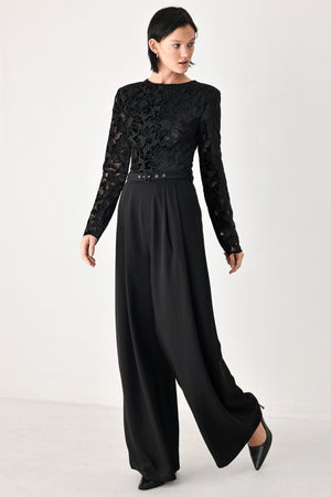 A woman modeling a black long-sleeve jumpsuit with a lace bodice and wide-leg trousers | FREEMARKET