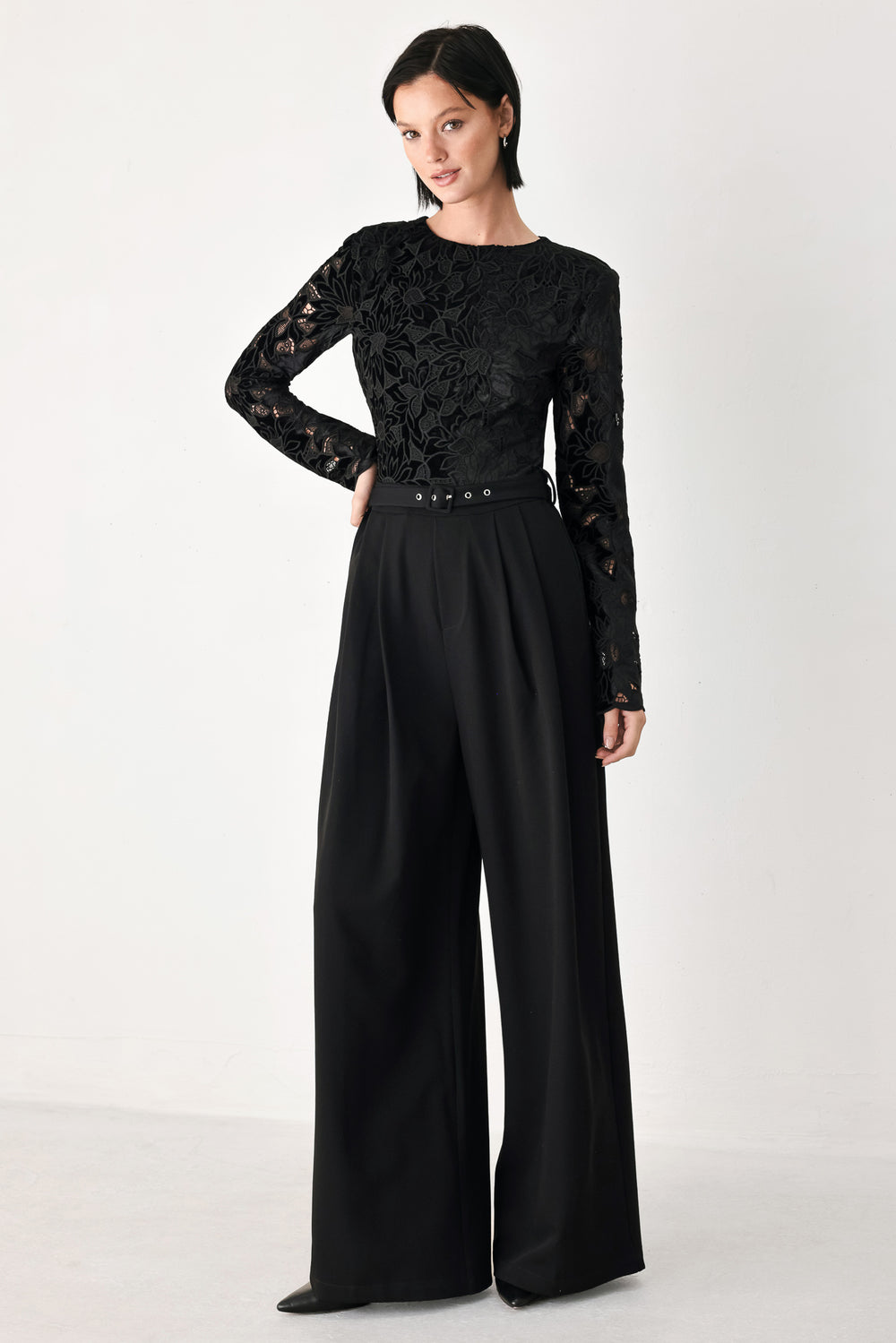 A woman modeling a black long-sleeve jumpsuit with a lace bodice and wide-leg trousers | FREEMARKET