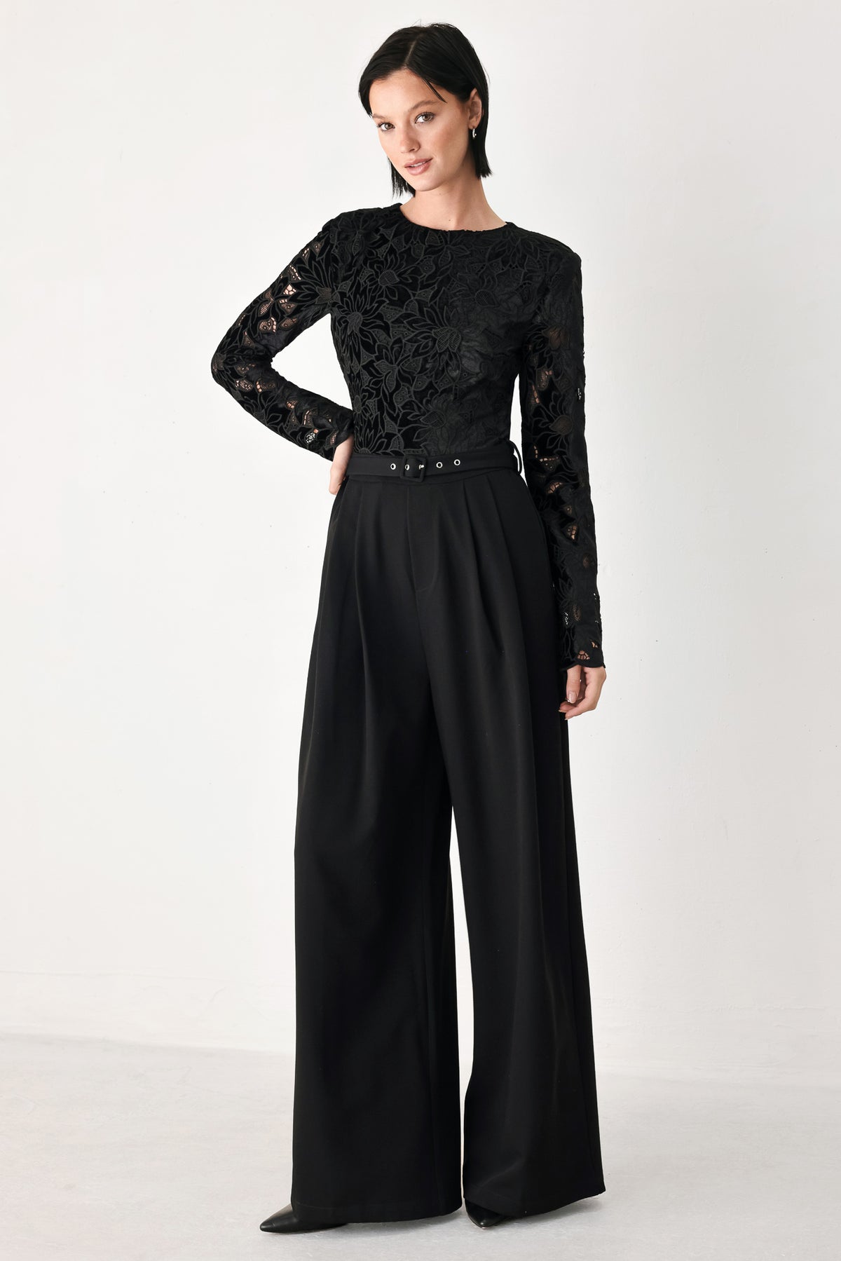 A woman modeling a black long-sleeve jumpsuit with a lace bodice and wide-leg trousers | FREEMARKET