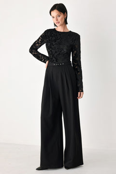 A woman modeling a black long-sleeve jumpsuit with a lace bodice and wide-leg trousers | FREEMARKET