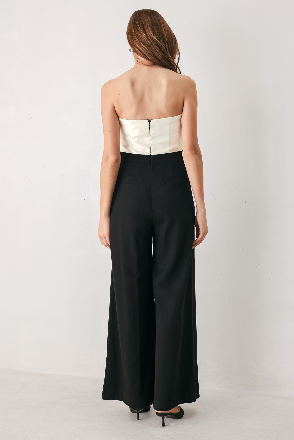 Woman wearing a strapless jumpsuit with white top and black bottom | FREEMARKET
