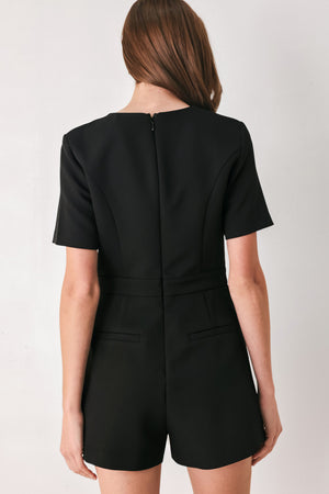 Woman wearing a black short sleeve romper with front keyhole and small embellished bows and pockets | FREEMARKET